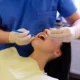 Dentist performing wisdom teeth removal on young woman using dental tools