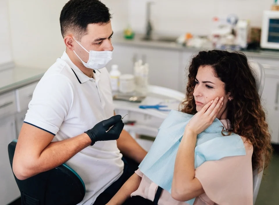 Dentist examining woman with wisdom tooth pain before wisdom teeth removal