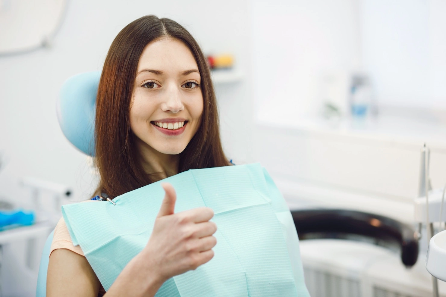 Girl showing thumbs up after wisdom teeth removal recovery with healthy smile