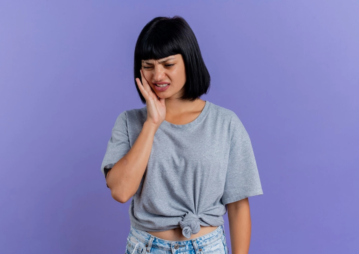 Young woman with cheek pain during wisdom teeth removal recovery at home