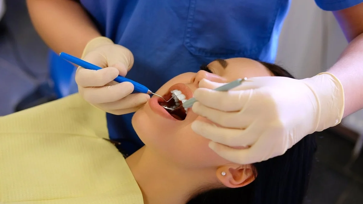 Wisdom teeth removal recovery with dentist treating young woman after oral surgery