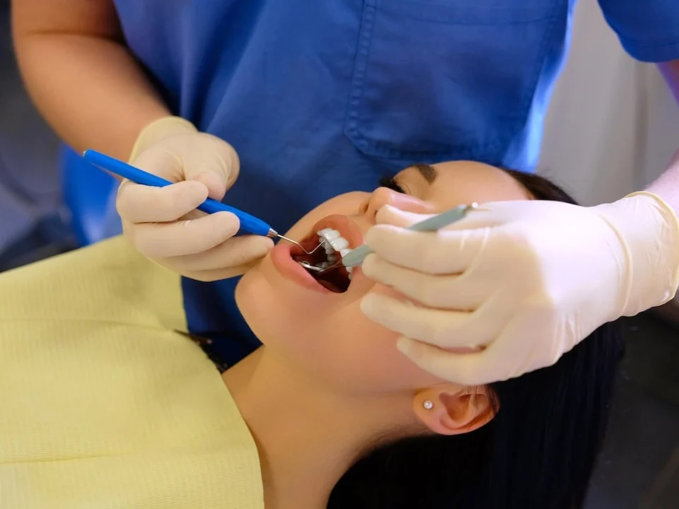 Wisdom teeth removal recovery with dentist treating young woman after oral surgery